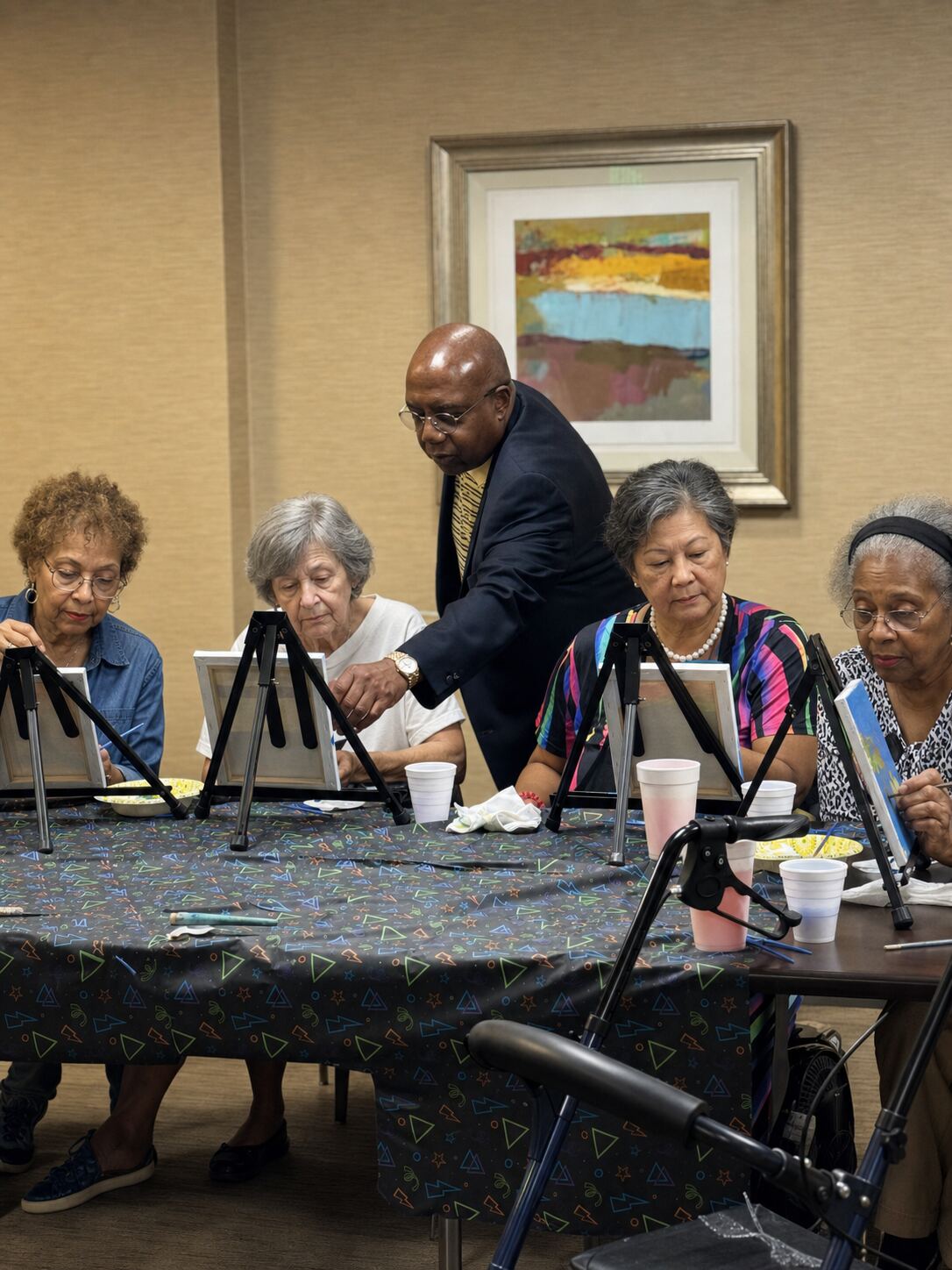 Elder Will Huff assisting seniors in a painting class at an In H.I.S. Care residential home